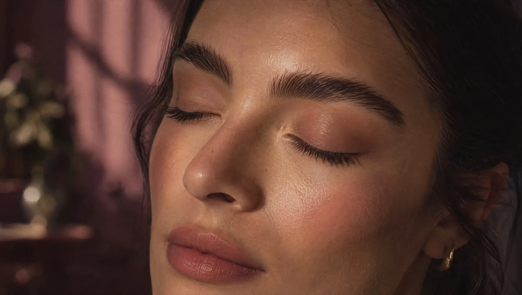 Close-up of full, softly brushed natural brows in warm window light
